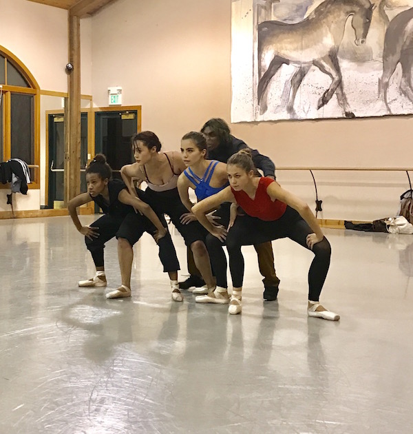 Members of BalletNext in leotard and rehearsal clothes squat in a second position near one another